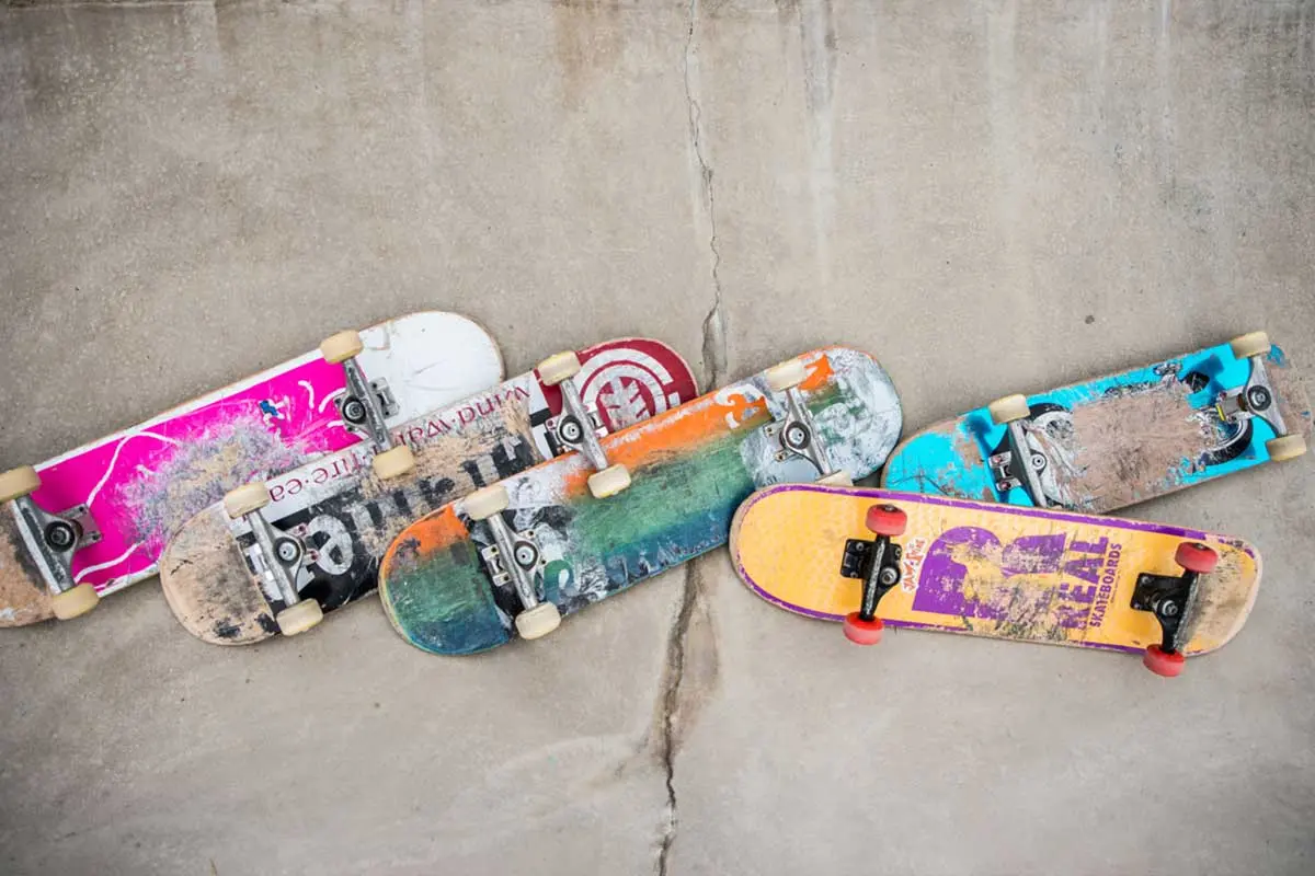 Fem färgglada skateboards ligger på en betongyta.