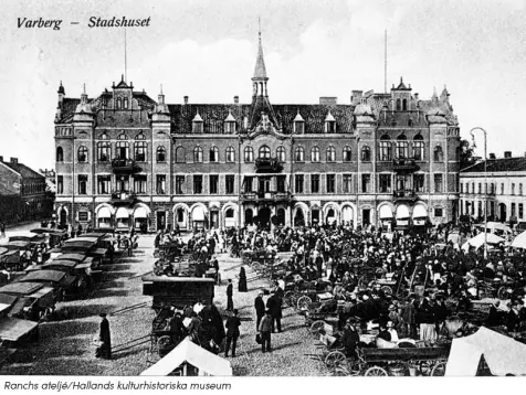 Varbergs stadhus, svartvit bild från 1910-talet. Torgdag med myller av människor och torgstånd i förgrunden. I bakgrunden en pampig byggnad med tornspiror.