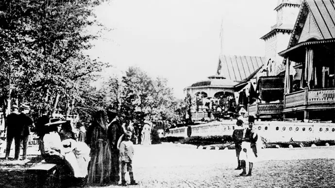 Societetsparken och societetshuset. Svartvitt foto från 1910-talet. En samling människor i förgrunden. I bakgrunden skymtas husets veranda.