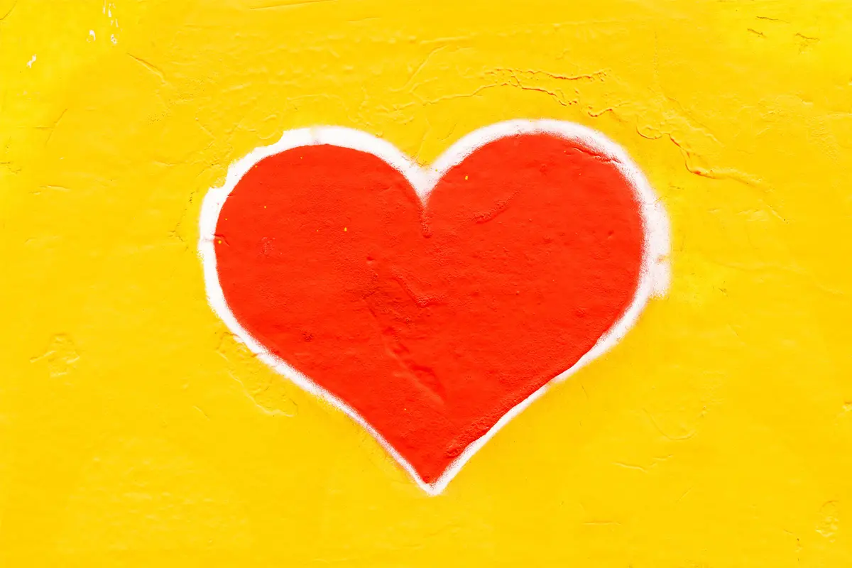 Ett målat rött hjärta på en gul bakgrund.