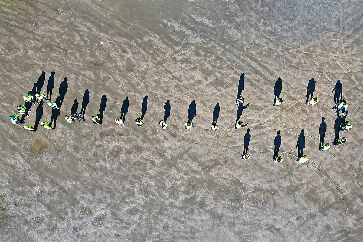 Bild tagen från luften där folk i varselväst har ställt sig i en formation som liknar en spade
