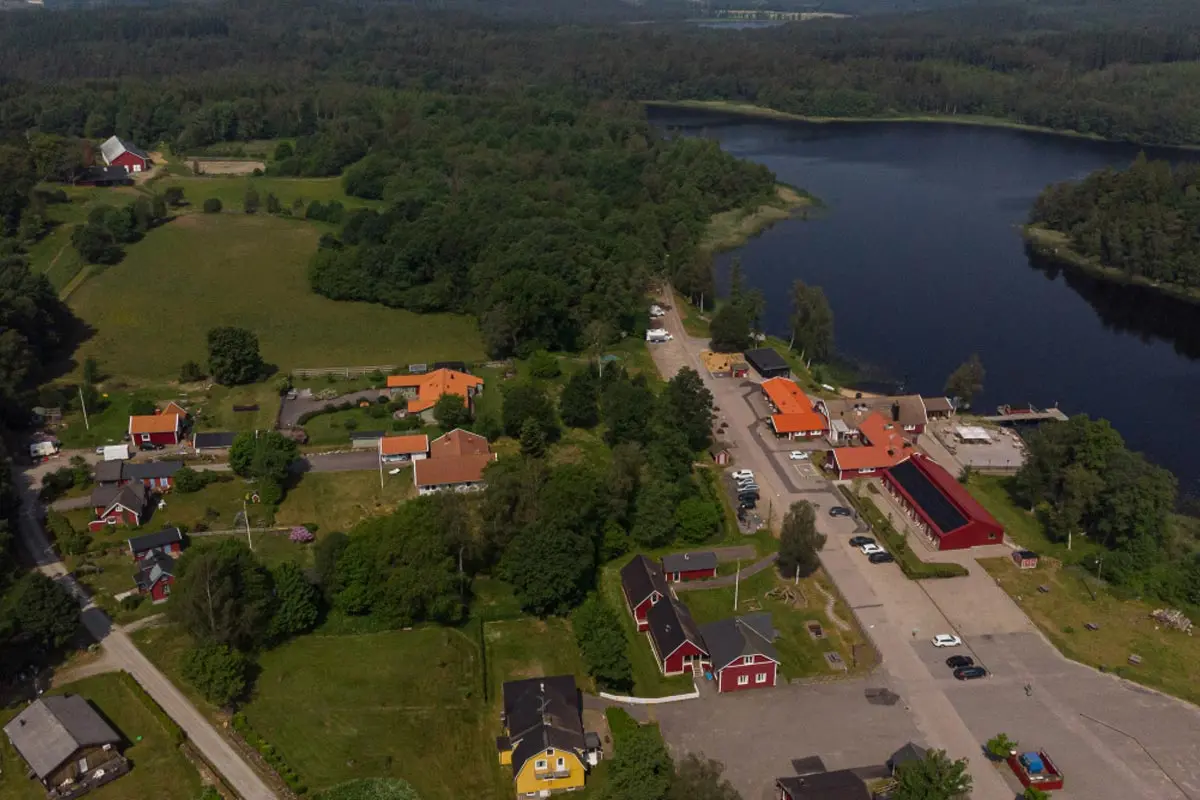 Drönarbild över Åkulla friluftsgård och omkringliggande byggnader. Yasjön till höger i bild.