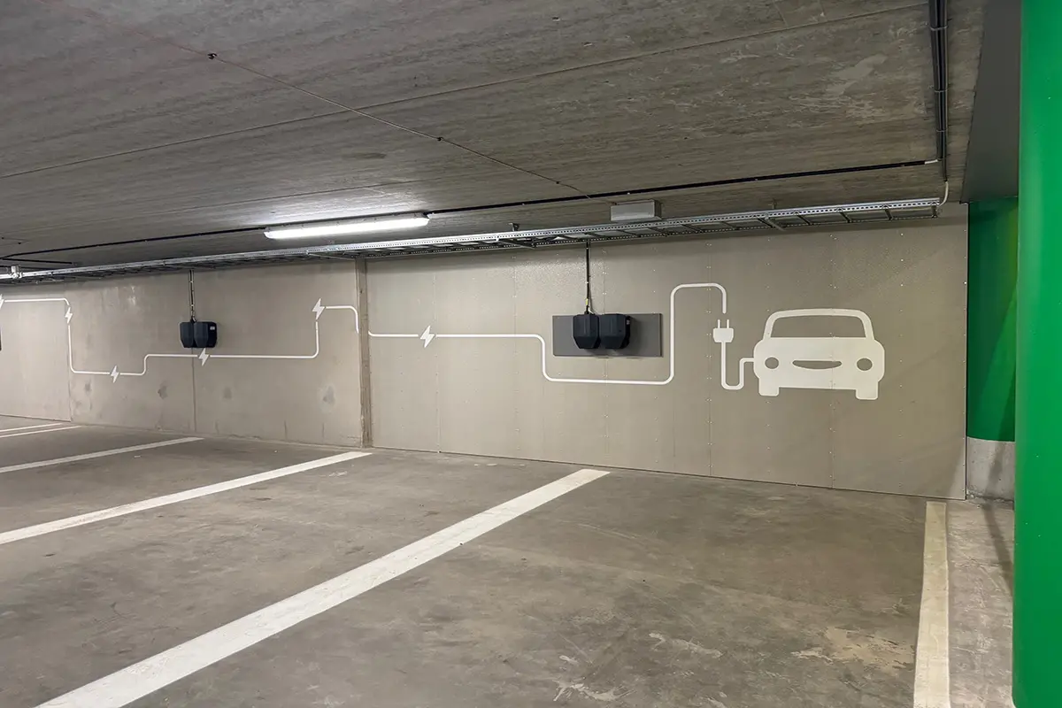 Parkeringsgarage med laddningsuttag för elbilar. På väggen är en ikon för elbil. 