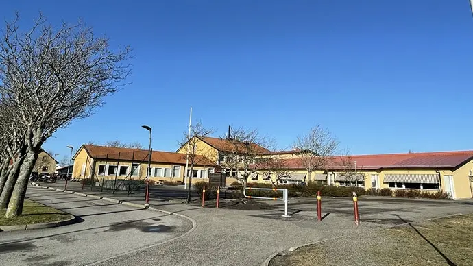 Väröbackaskolan i Varberg. En ljust gul träbyggnad i olika plan. Rött tegeltak.