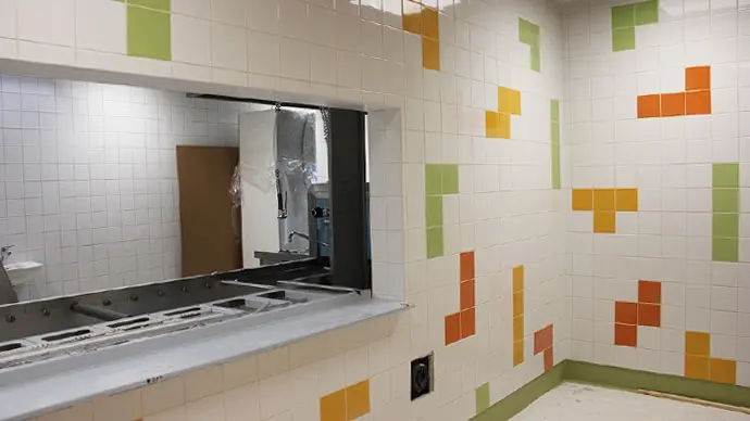 Bua förskolas matsal. Vitt kakel med inslag av färgade plattor i grönt, gult och orange skapar livfulla väggar.