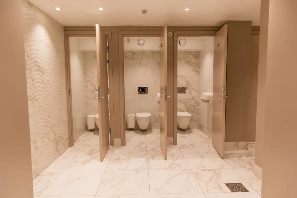 Nyrenoverade toaletter på Societetshuset i Varberg. Mjukt nogatfärgade väggar matchat med marmorerat kakel och klinker i samma nyanser. Dörrarna till toalettbåsen är öppna.