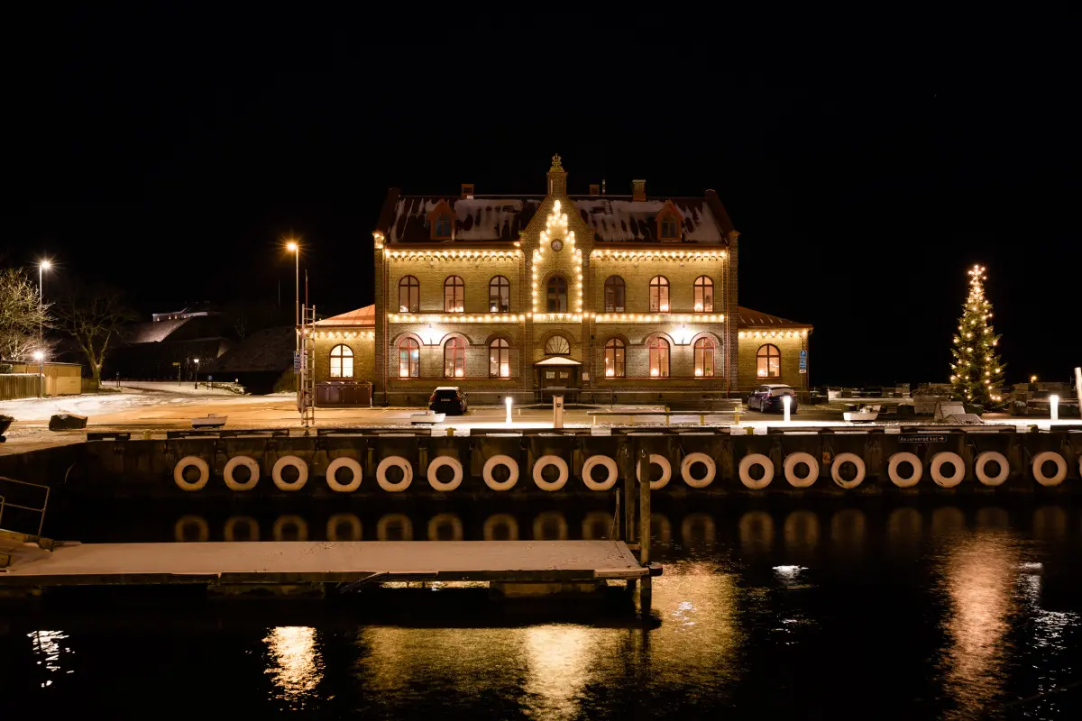Tullhuset i Varberg, nattfoto i juletid. Små lampor likt pärlband längs husets tak och utsmyckningar.