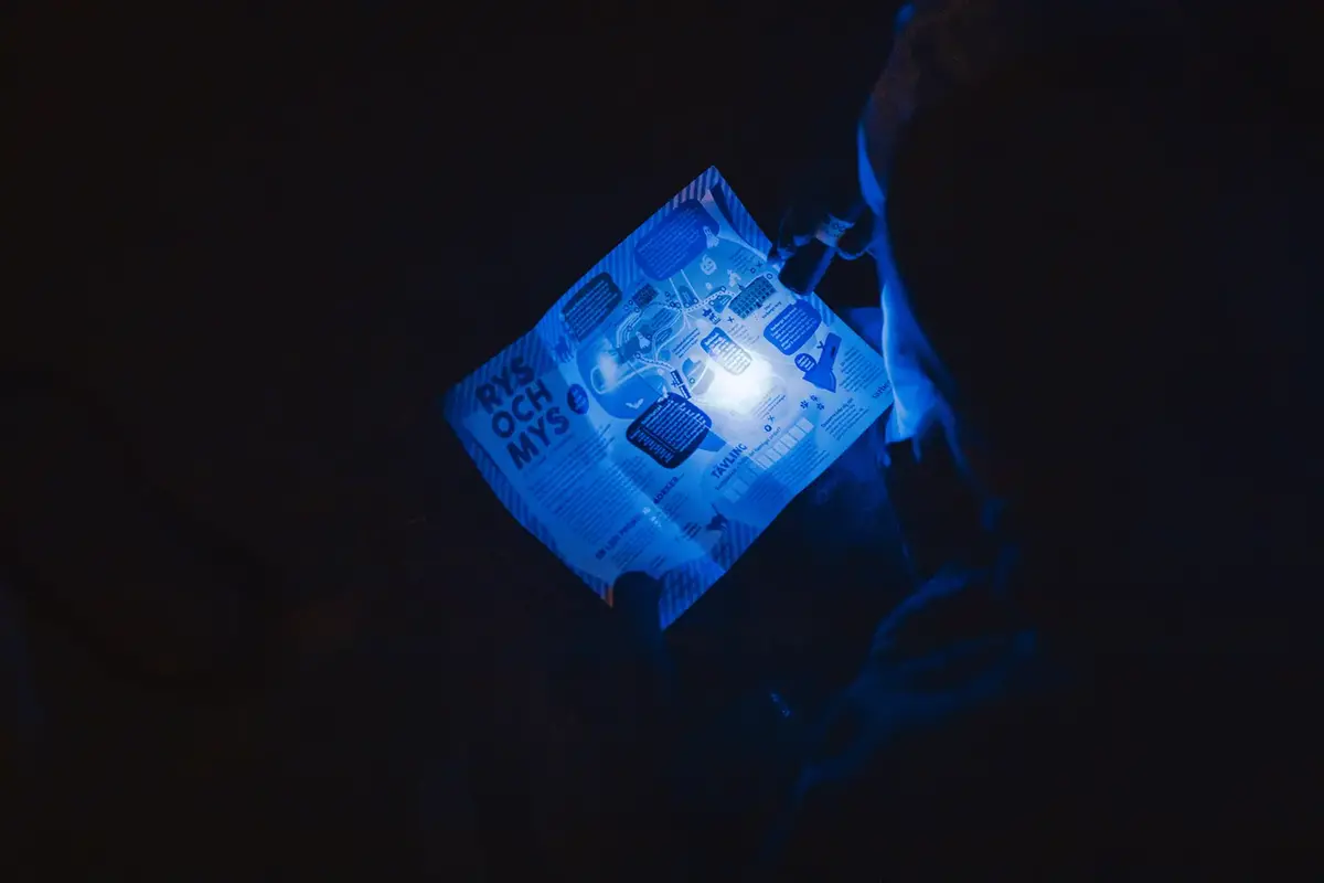 En person står i mörkret med en karta och lyser med ficklampa.