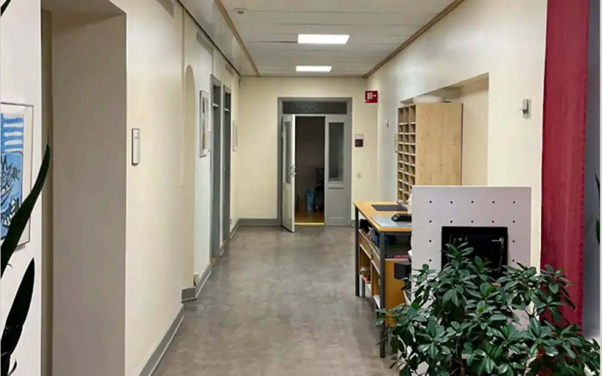 En korridor i en kontorsmiljö. En grön växt och förvaring på höger sida. 