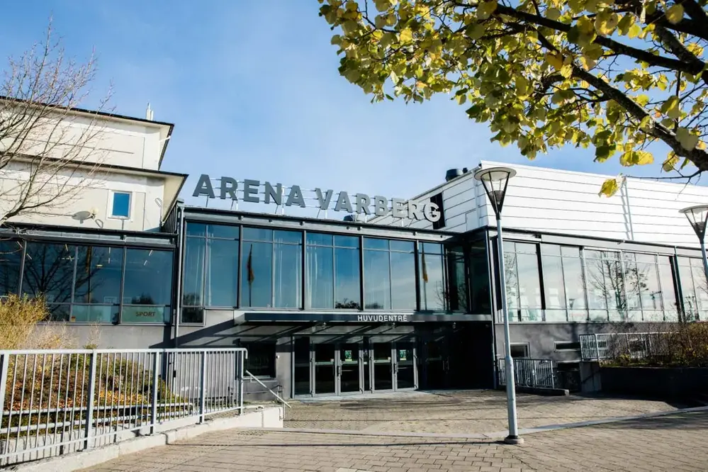 Närbild på Arena Varbergs stora entré. Långsträckt byggnad med stora glaspartier. En trappa leder ner till entrén.